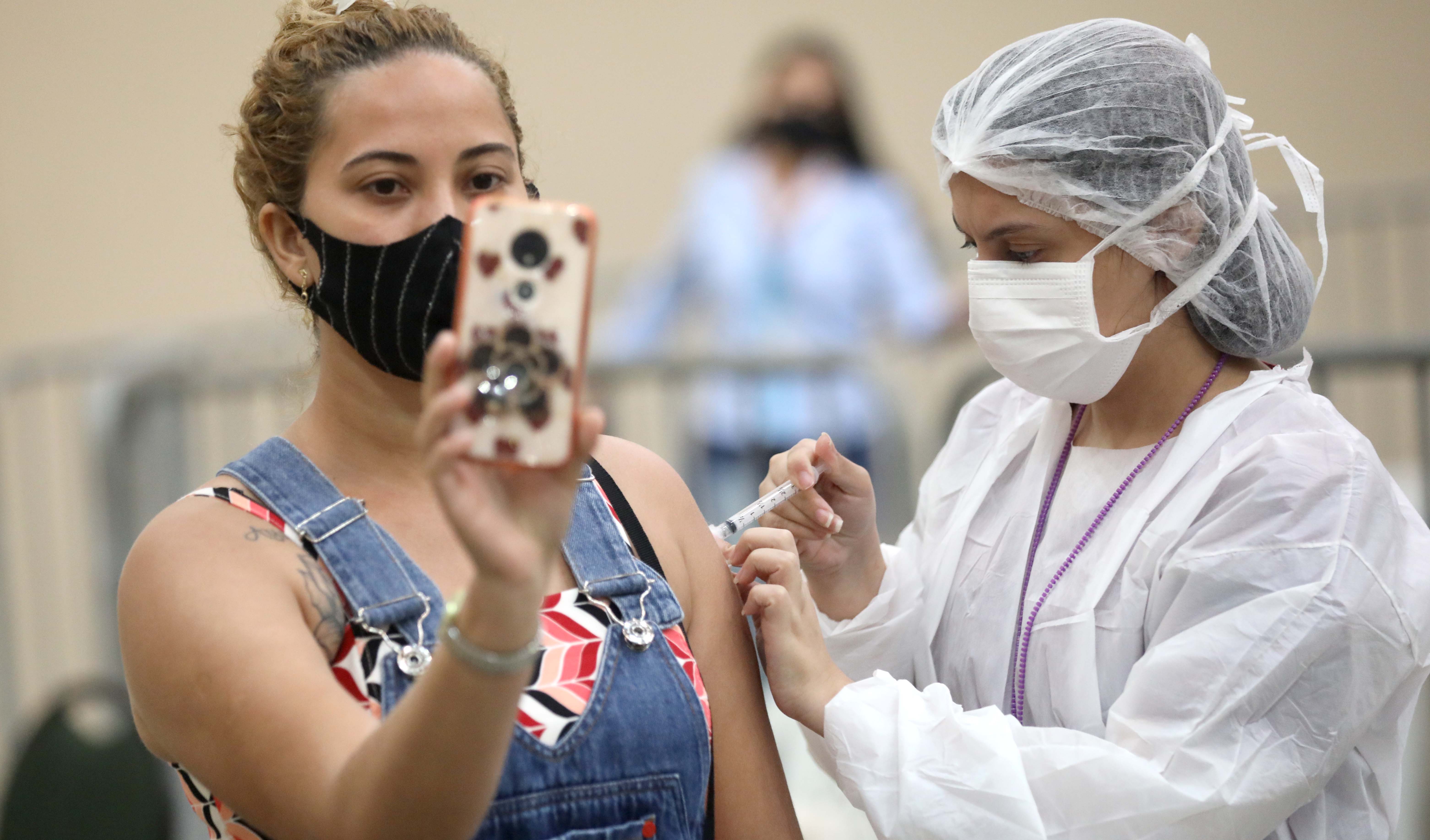 mulher fazendo selfie enquanto se vacina